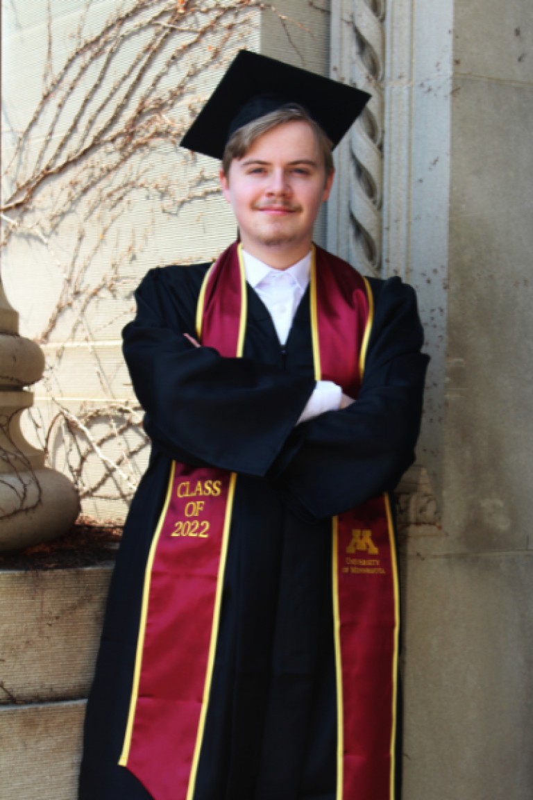 Nick stands in cap and gown