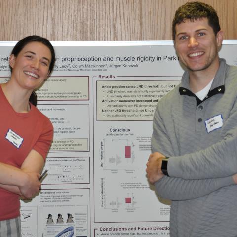 Graduate students in front of research poster. 